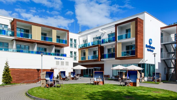 Een modern hotel met een receptie, terras en een trap.