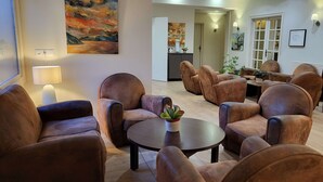 A spacious living area with leather armchairs, a round coffee table, and a painting on the wall.