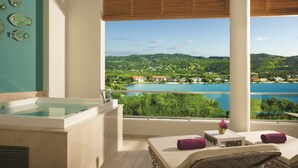 A spa area with a bathtub, seating, and a view of a lake and greenery.