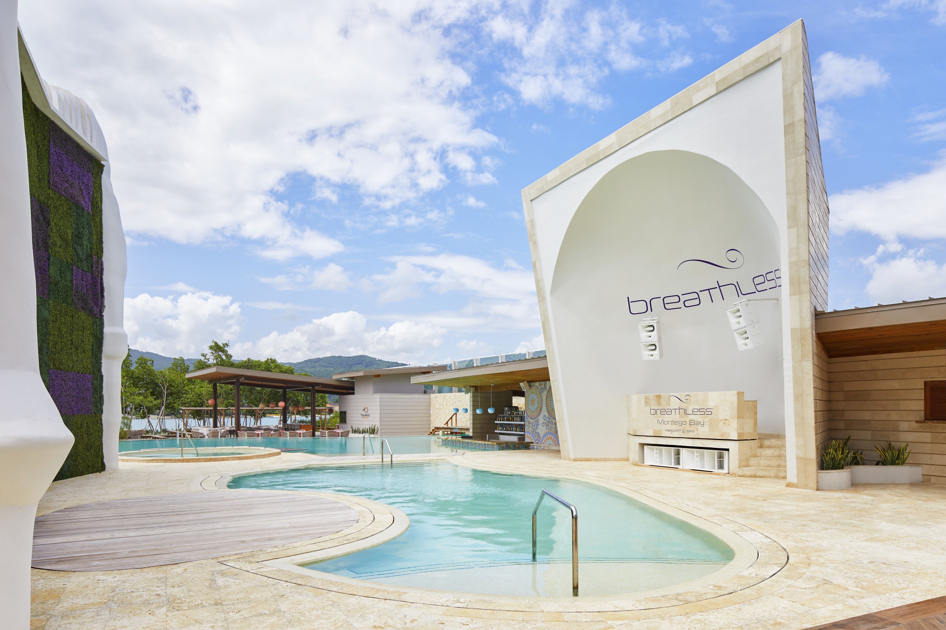 A pool area with a clear sky, a building with 'breathless' signage, and a mountain in the background.