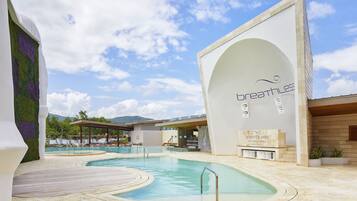A pool area with a clear sky, a building with 'breathless' signage, and a mountain in the background.