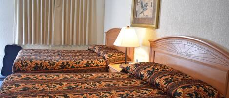 A hotel room with two beds, a lamp, and a window with curtains.