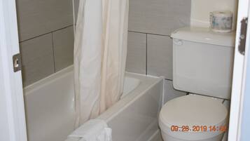 Un baño con bañera, inodoro y cortina de ducha.