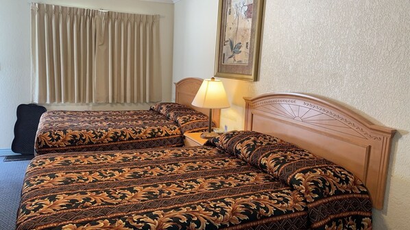 Una habitación de hotel con dos camas, una lámpara y un cuadro en la pared.