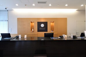 A hotel reception desk with a modern design, a logo, and a reception counter. - Hotel Urbic Kagoshima (Kagoshima)