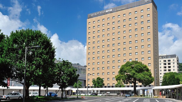Um hotel com vários andares, fachada uniforme e telhado plano, com uma placa indicando ser um hotel.