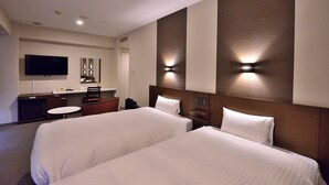 Quarto de hotel com duas camas, uma escrivaninha, uma cadeira, uma televisão e um espelho.