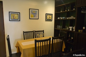 Comedor con una mesa dispuesta para cuatro personas, obras de arte en la pared y una vitrina china con vajilla.