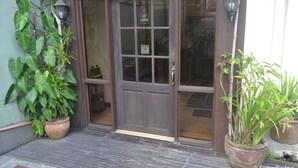 A wooden door with a glass panel, flanked by potted plants. - Twin Pines Suites (Tagaytay)