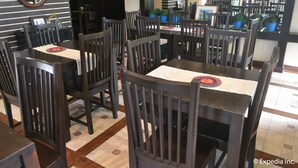 A dining area with wooden tables and chairs, a patterned table runner, and potted plants on the tables. - Twin Pines Suites (Tagaytay)