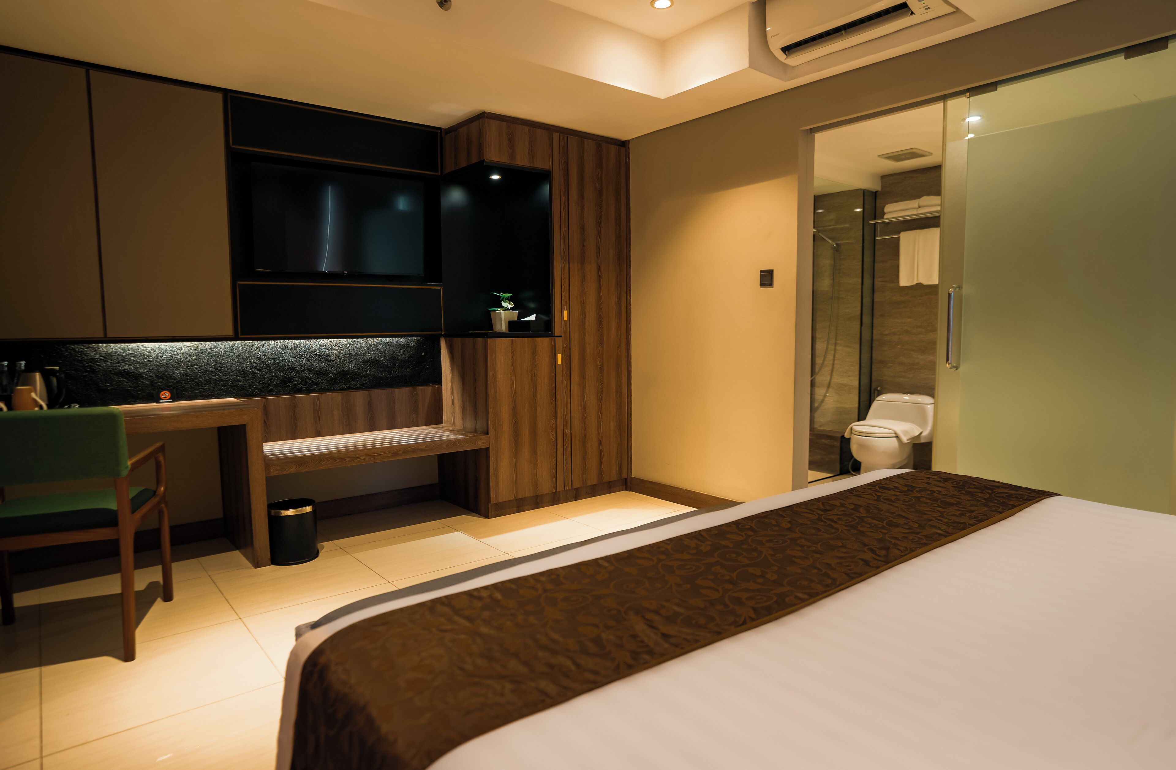Une chambre d’hôtel moderne équipée d’un lit, d’un bureau, d’une chaise, d’une télévision et d’un espace douche.