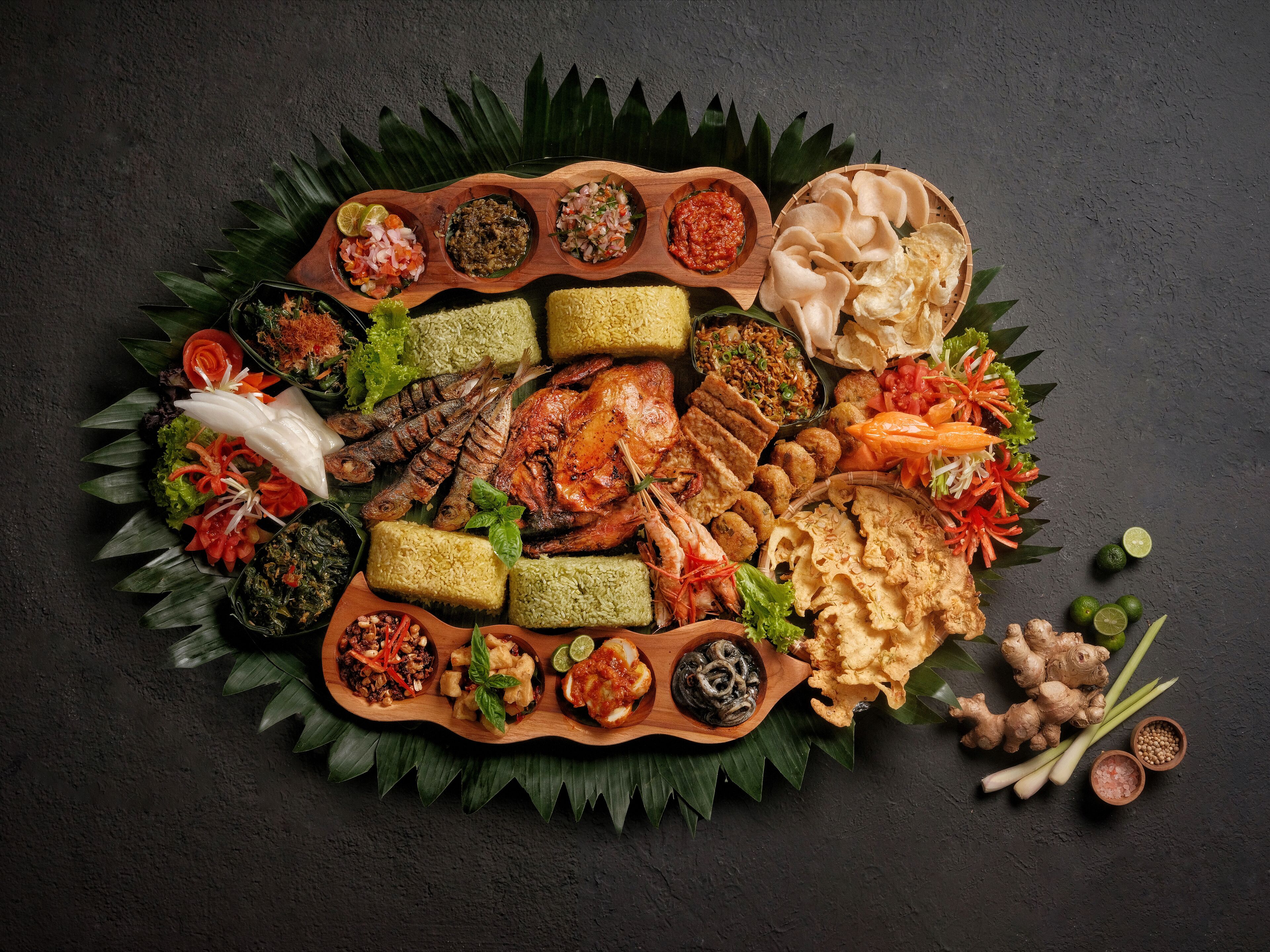 A variety of dishes and ingredients arranged on a wooden platter with a dark background.