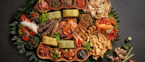 Una variedad de platos e ingredientes dispuestos sobre una bandeja de madera sobre un fondo oscuro.
