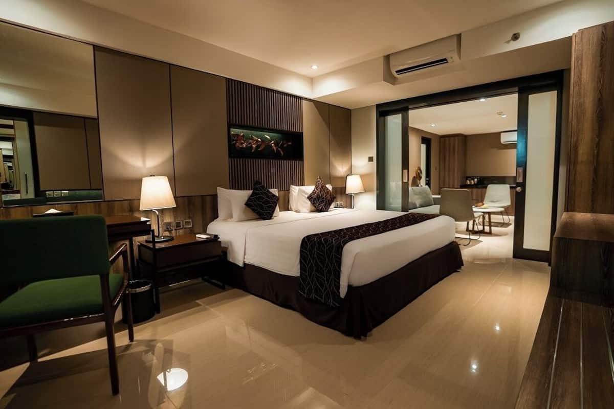 Ein modernes Hotelzimmer mit einem großen Bett, einem Schreibtisch, einem Stuhl und einem Essbereich.
