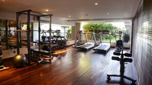 A gym with exercise equipment, a wooden floor, and large windows.