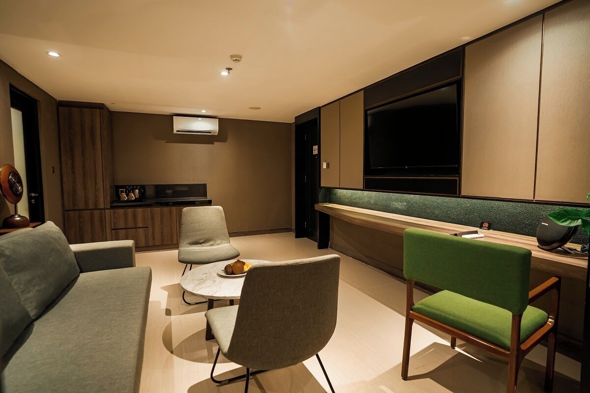 Uma sala de estar moderna com sofá, cadeiras, uma mesa pequena e uma área de cozinha com televisão.