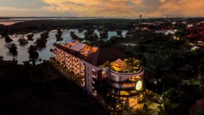 Um hotel com vários andares, um edifício circular com um letreiro iluminado em destaque e vista para o cais.