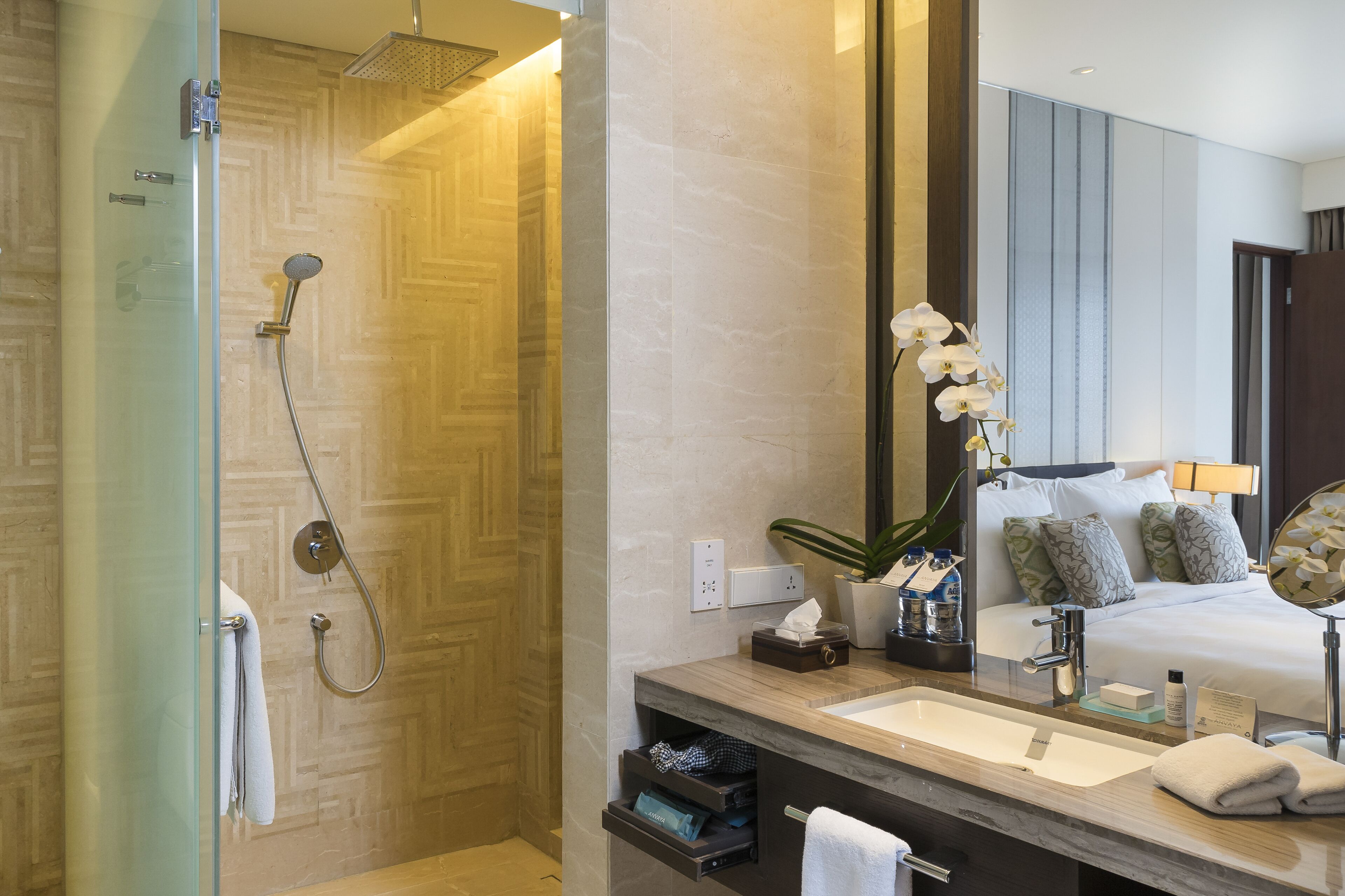 A modern bathroom with a glass-enclosed shower, a wooden vanity with a sink, and a large mirror.