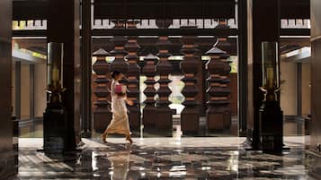 A spacious lobby with a polished marble floor, a traditional wooden gate, and a modern glass partition.