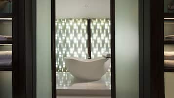 A modern bathroom with a freestanding bathtub, glass doors, and a towel rack.