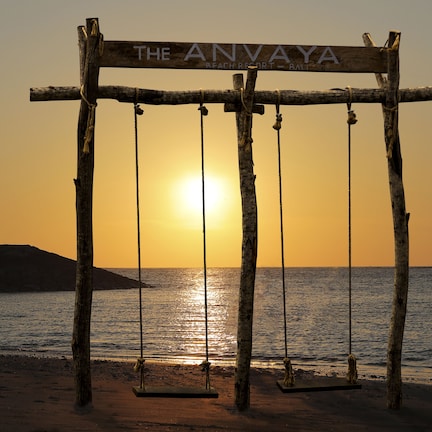 A wooden swing set with ropes, labeled "The Anvaya Beach Resort - Bali," against a sunset backdrop.