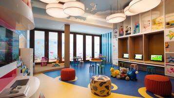 A children's play area with colorful furniture, a large window, and a ceiling with hanging lights.