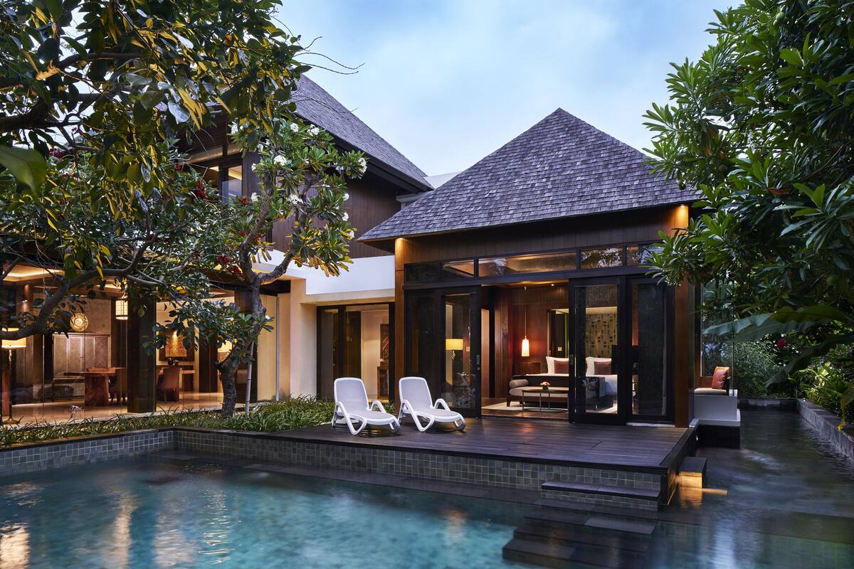 A modern resort with a swimming pool, lounge chairs, and a covered outdoor seating area.