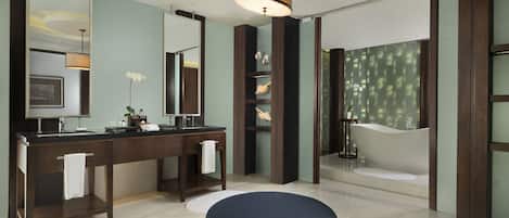 Un baño moderno con tocador doble, una bañera independiente y un espejo grande.