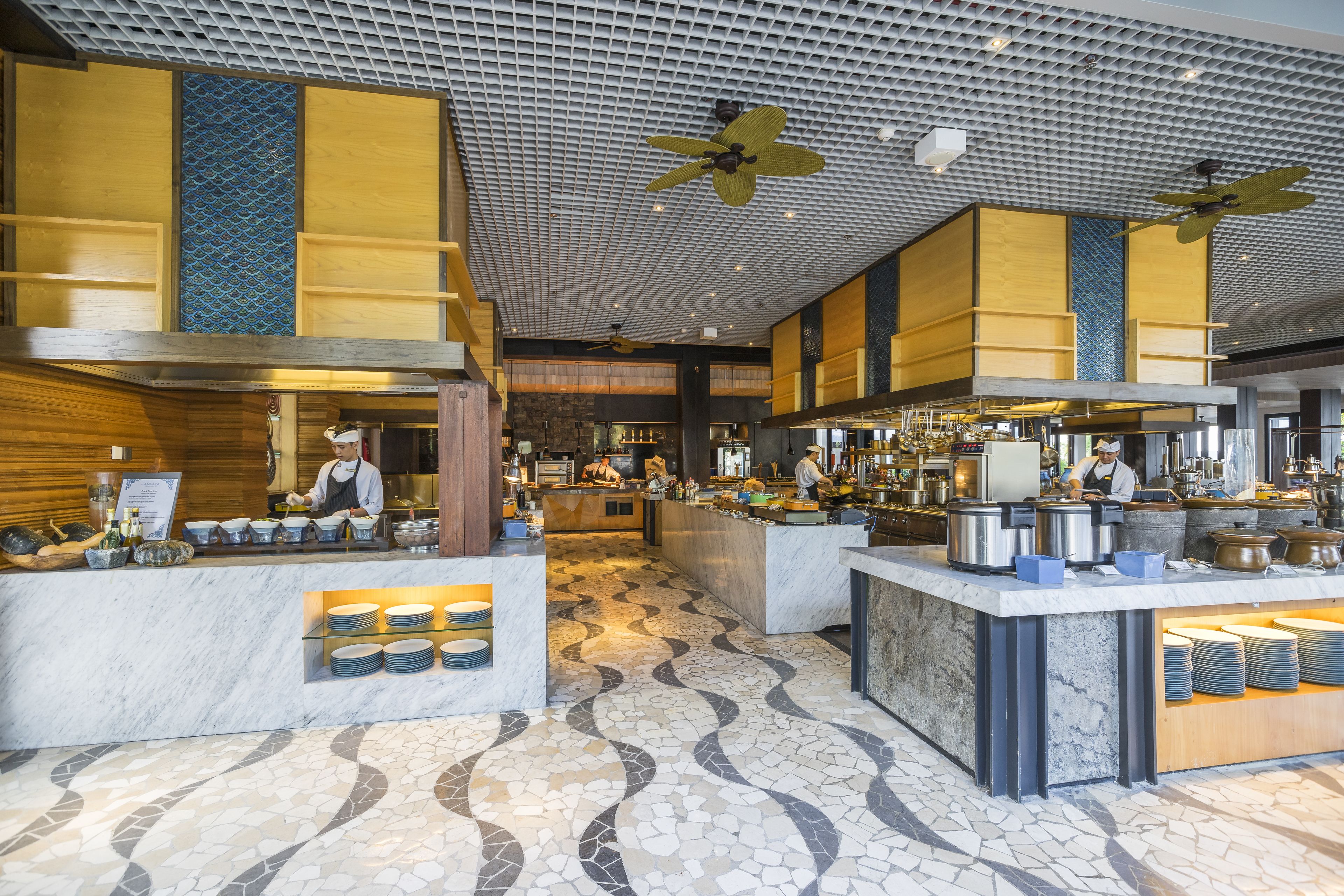 A modern restaurant with a central island, multiple ceiling fans, and a patterned floor.