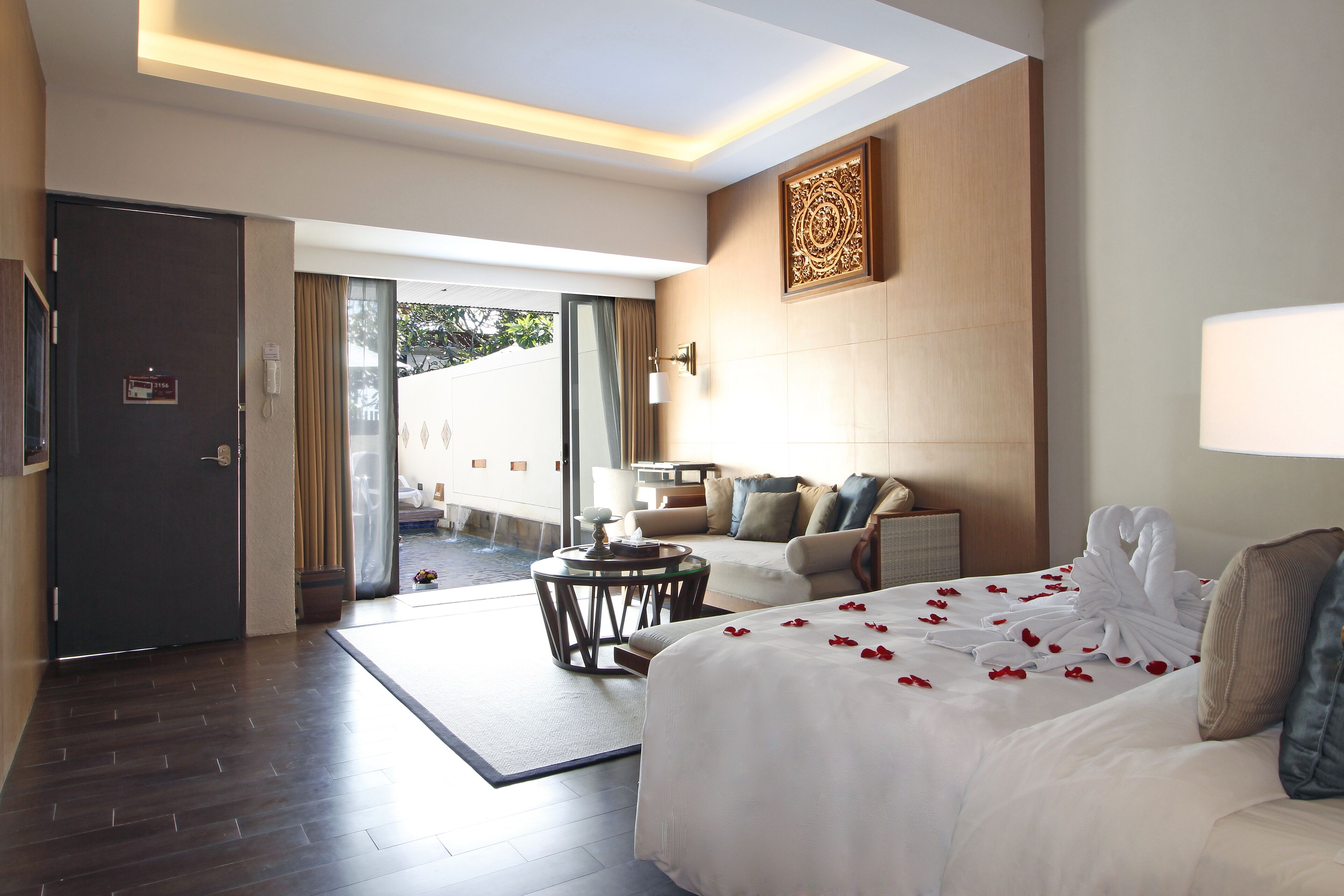 Habitación de hotel con cama, sofá, una mesita redonda y vistas al exterior.