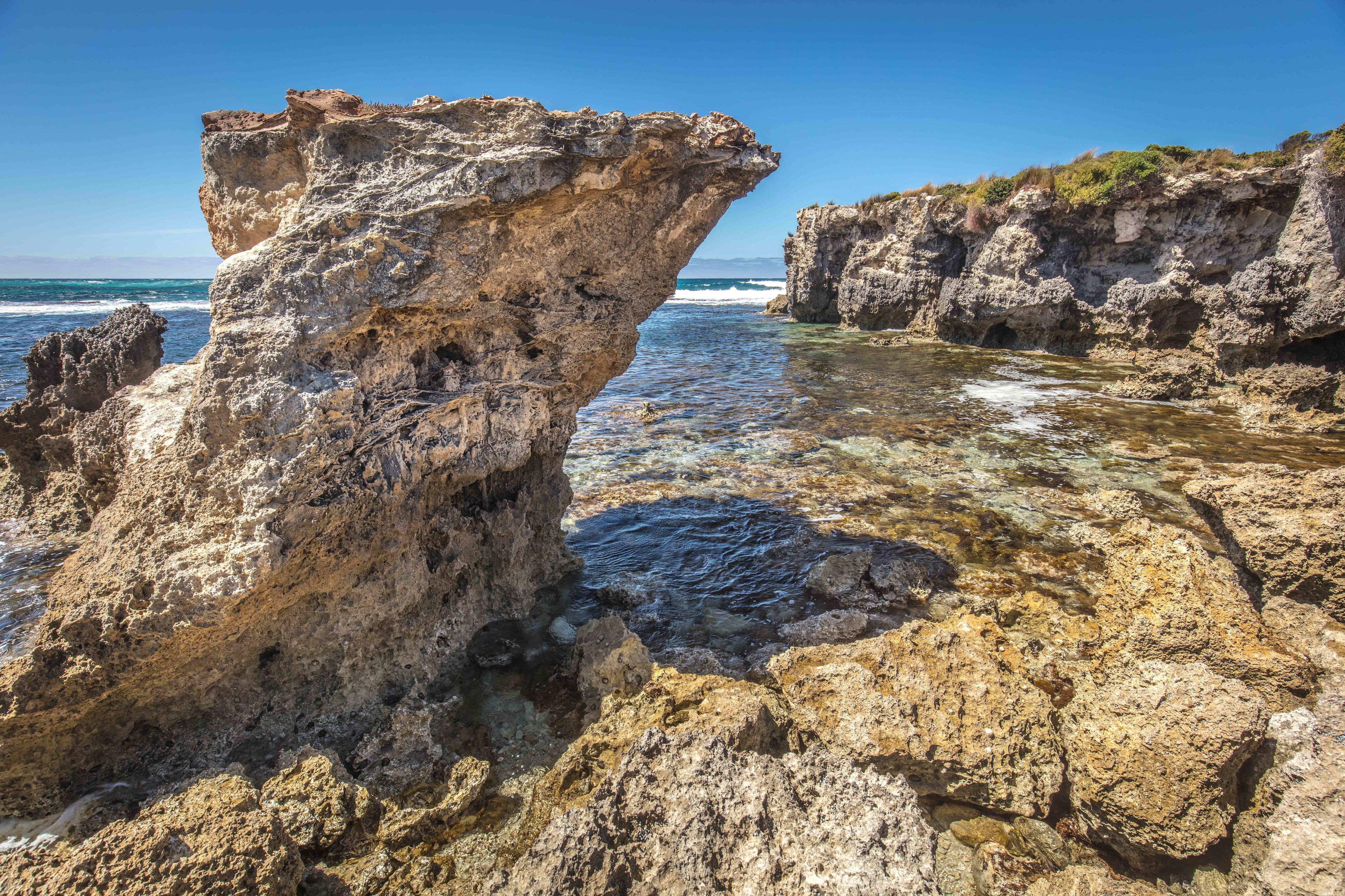 Un paysage côtier rocheux, caractérisé par une eau limpide et une formation rocheuse imposante.