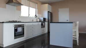 A modern kitchen with white cabinetry, a built-in oven, a microwave, and a refrigerator.