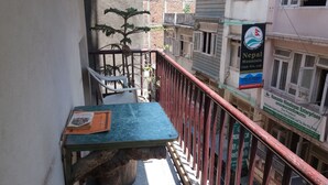 Un balcón con una mesa, sillas y una planta en maceta.
