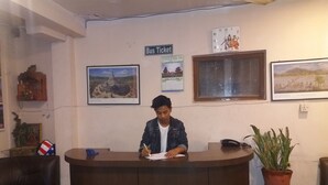 Una recepción con una persona escribiendo, un reloj y un cuadro en la pared.