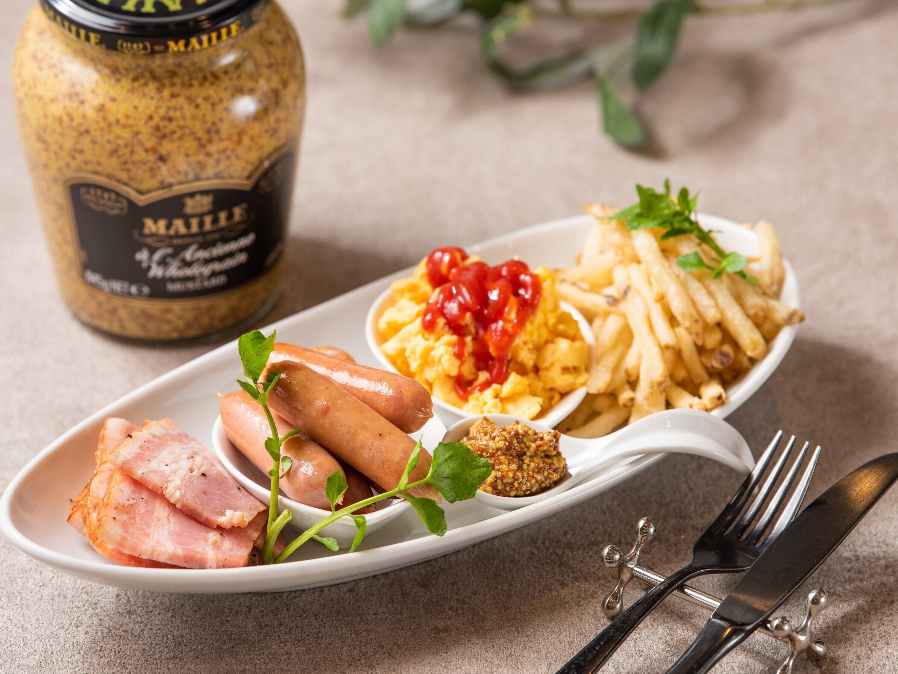 A plate with sausages, scrambled eggs, French fries, and a condiment.