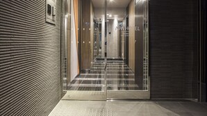 A modern hotel entrance with a checkered floor, a glass door, and a metal railing. - APA Hotel Ochanomizu Ekikita (Tokyo)