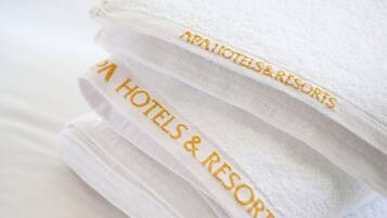 Uma pilha de toalhas brancas com bordado que diz "AAA HOTELS & RESORTS".