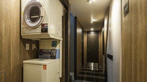 A hotel corridor with a washing machine, a scale, and a sign indicating the lobby. - APA Hotel Ochanomizu Ekikita (Tokyo)