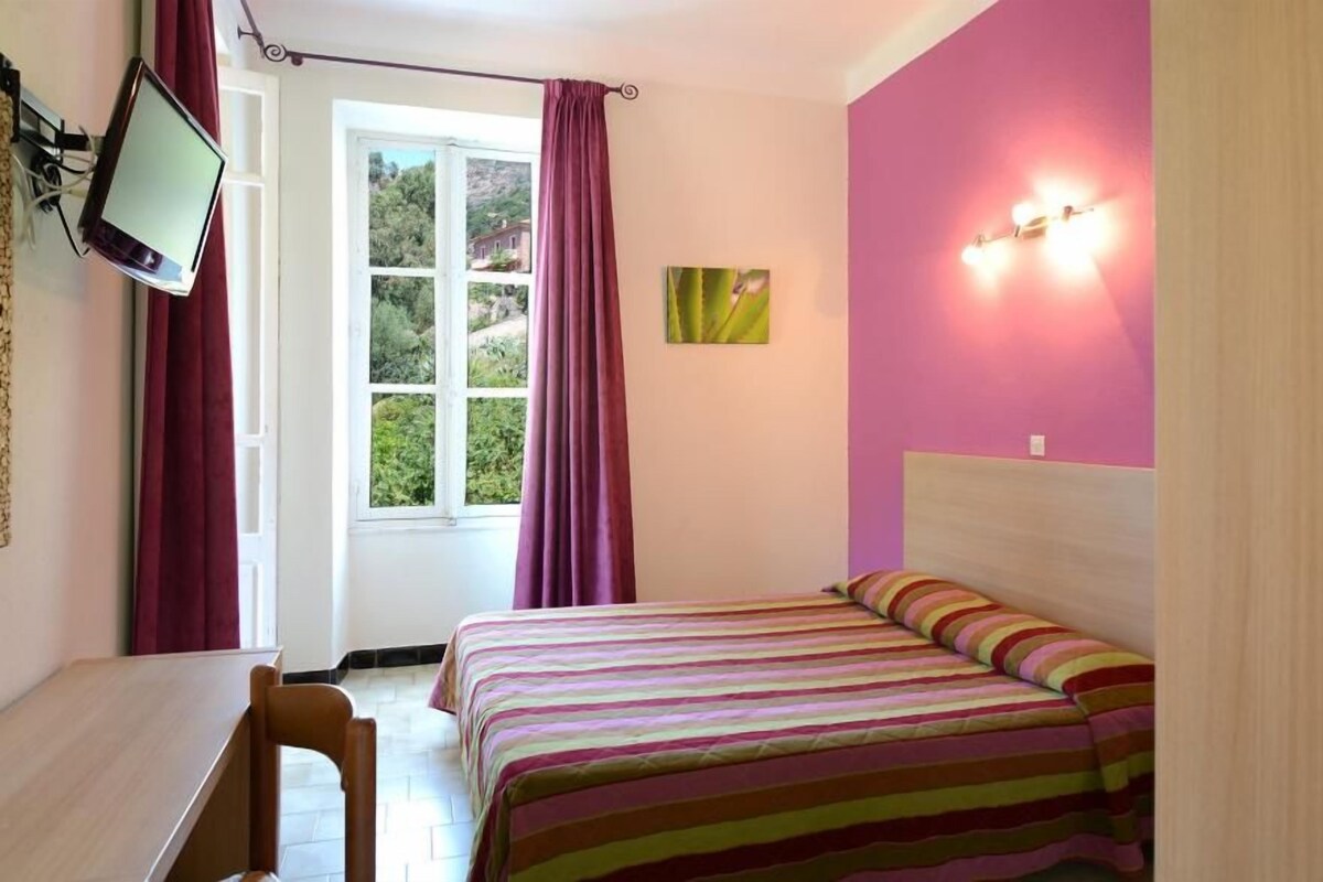 Un dormitorio con una cama, un escritorio y una ventana con cortinas.