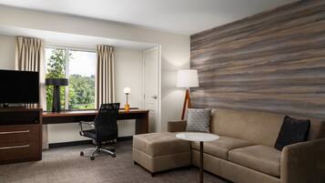 Een hotelkamer met een bureau, een televisie, een bank en een lamp.