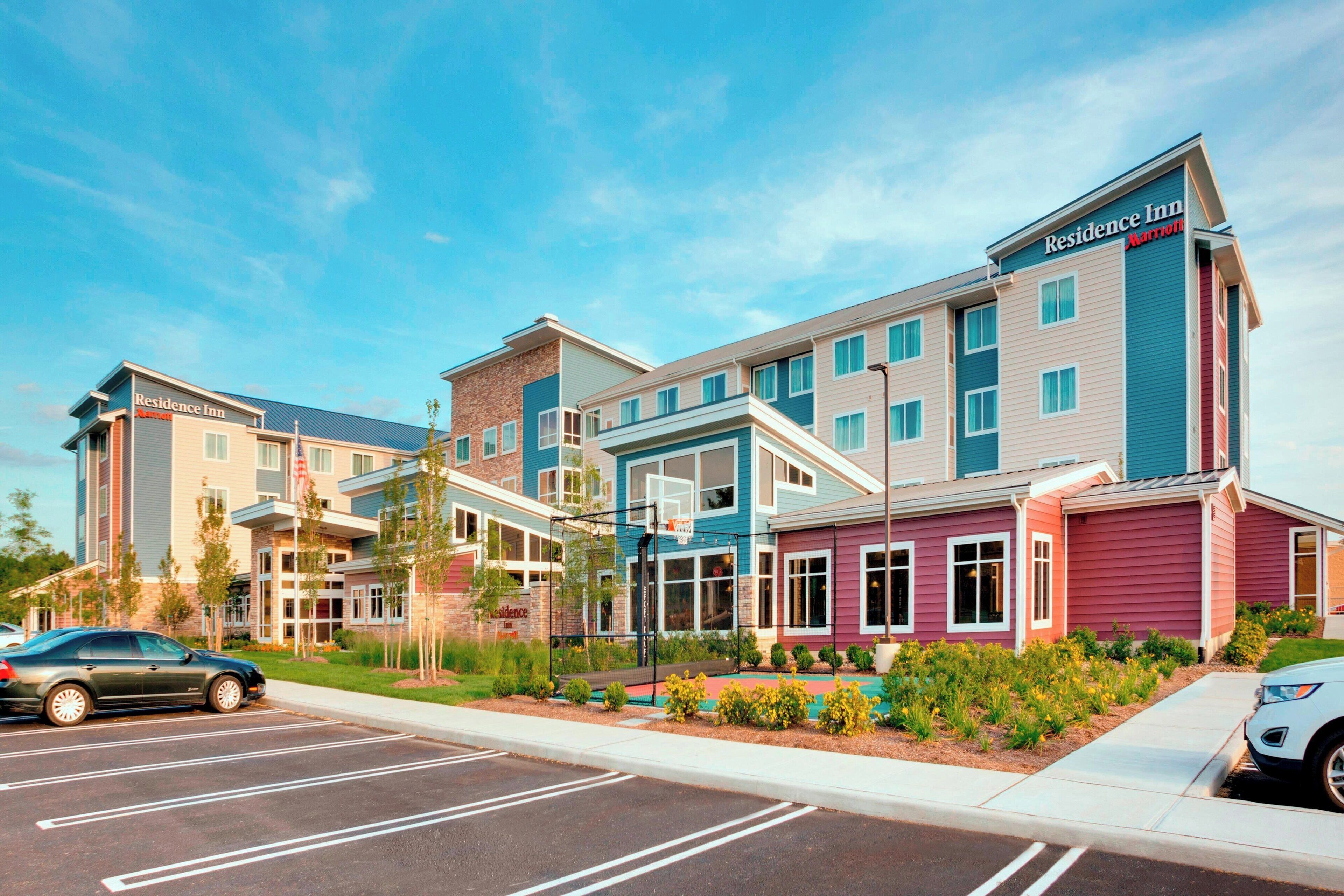 A multi-story hotel with a modern design, featuring a mix of colors and a parking lot in front.