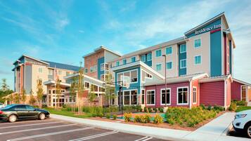 A multi-story hotel with a modern design, featuring a mix of colors and a parking lot in front.