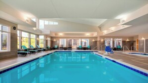 Una piscina interior con sillones de descanso y vistas al exterior.