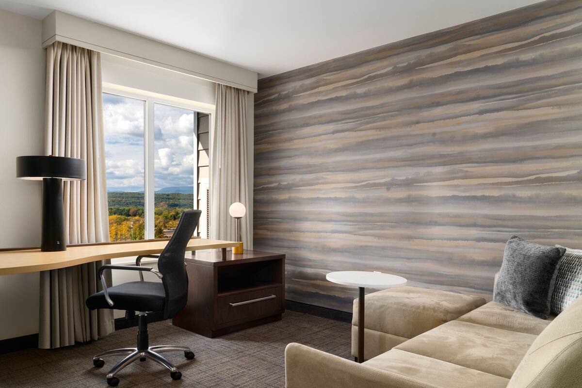 Ein Hotelzimmer mit Schreibtisch, Bürostuhl und einer Sitzecke.