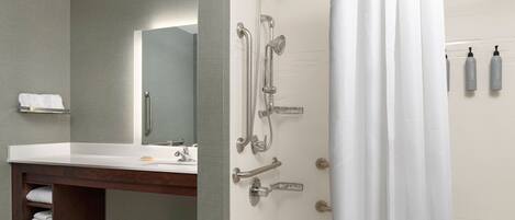 Un baño moderno con lavabo, espejo, ducha y artículos de aseo.