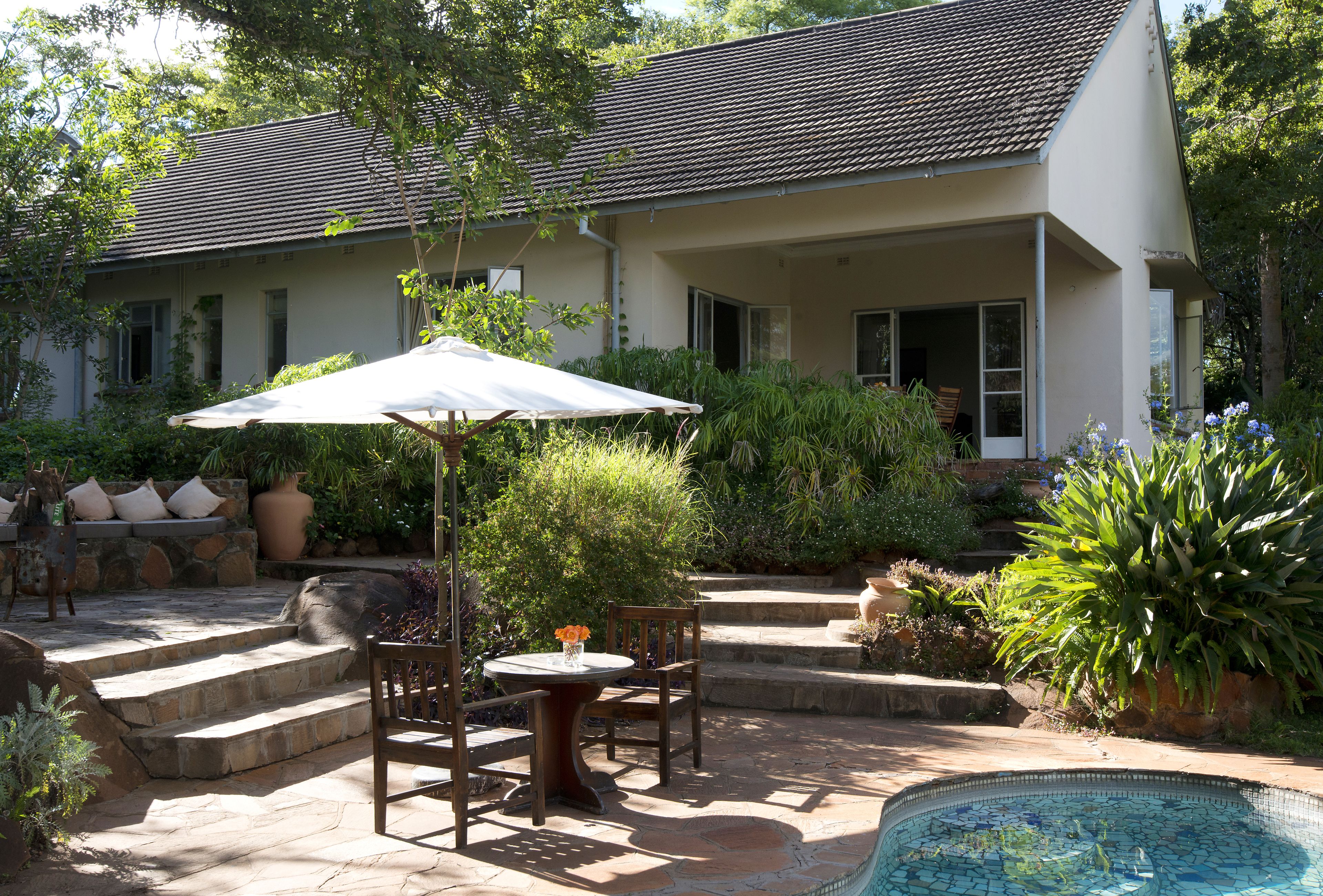 A house with a patio area featuring a pool, outdoor furniture, and a covered seating area.