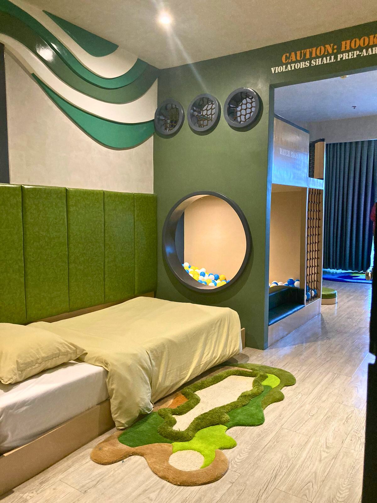 Una habitación con una cama, un espejo circular, un reloj en la pared y un letrero de precaución.