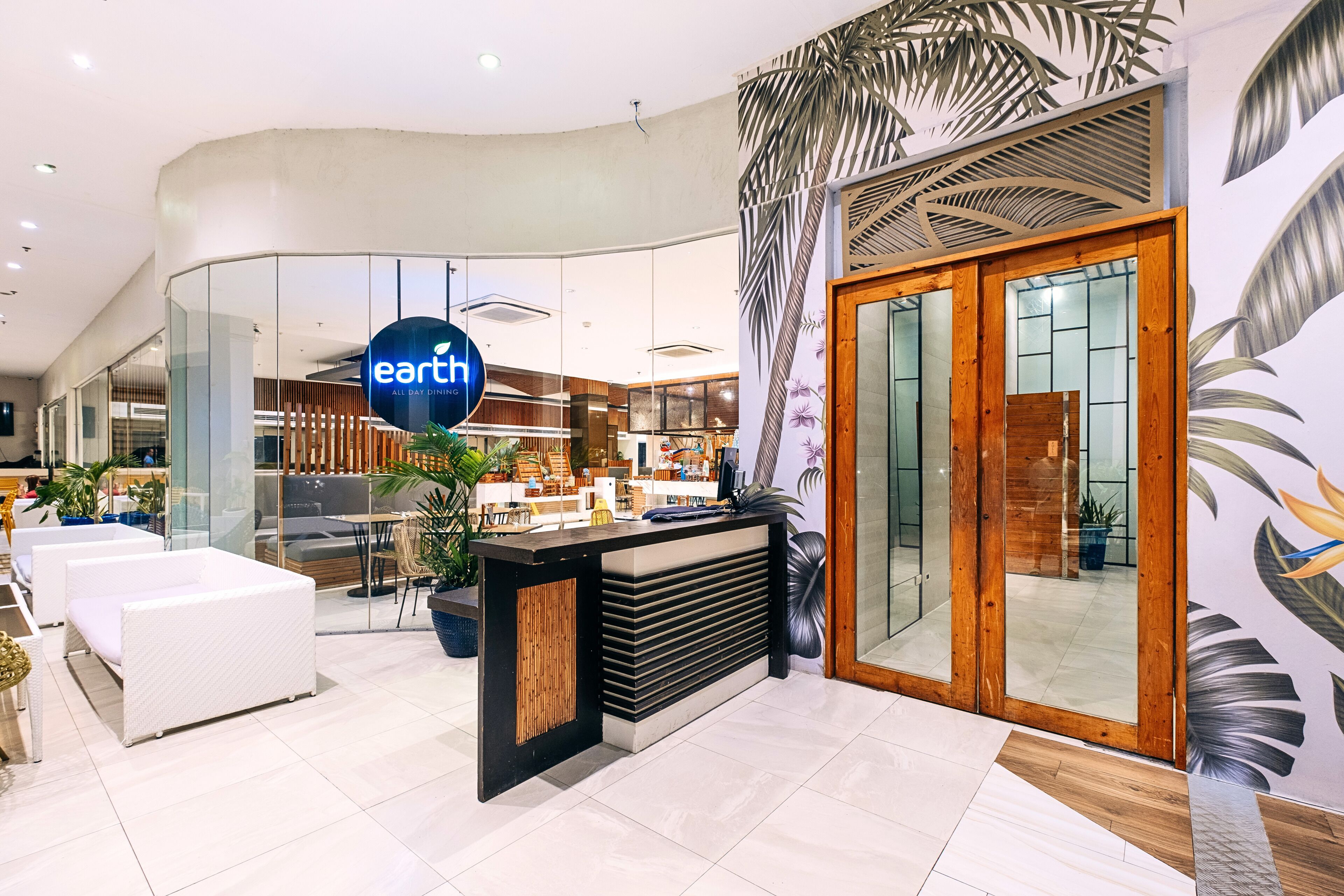 Een modern interieur met een receptiebalie, een zithoek en uitzicht op de eetruimte.