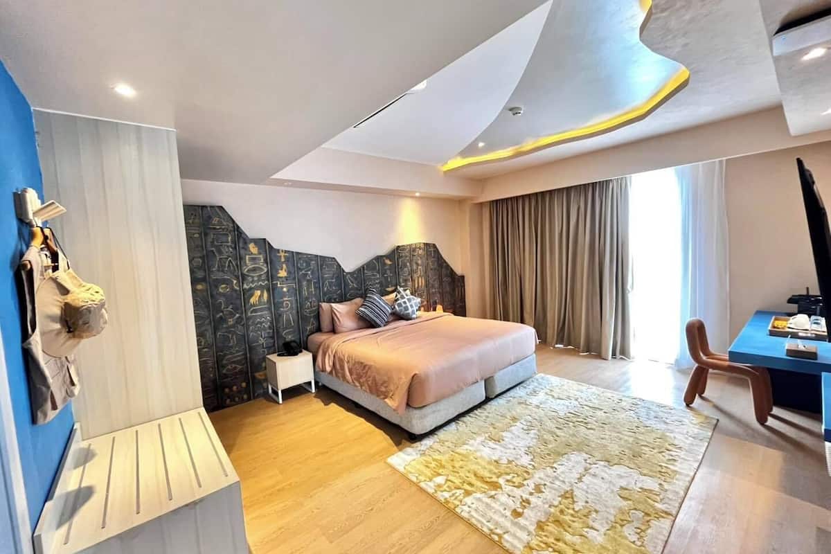 Una habitación de hotel moderna con una cama grande, un escritorio y vistas a la ciudad.