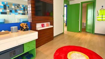 A room with a wooden vanity, a mirror, a red rug, and a green door.
